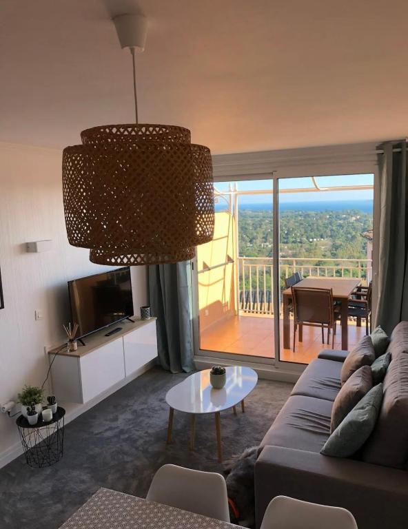 un salon avec un canapé et une grande fenêtre dans l'établissement Les Restanques Duplex 4 pers Les Magnolias Magnifique vue mer, à Grimaud