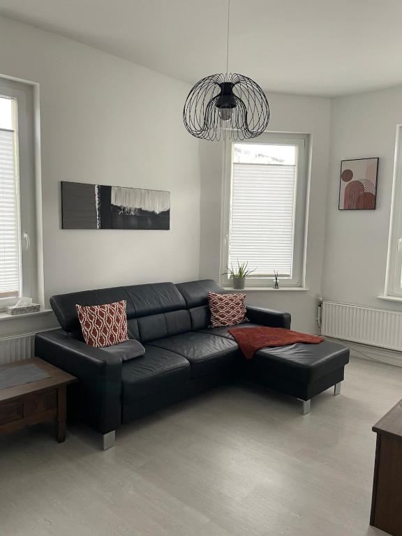 ein Wohnzimmer mit einem schwarzen Ledersofa in der Unterkunft Apartment im Herzen von Lübeck in Lübeck