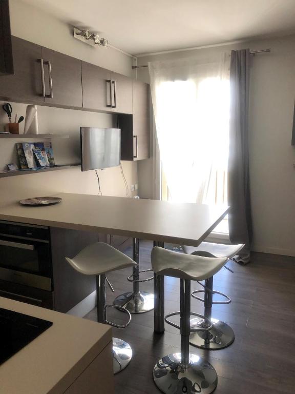 une cuisine avec une table et deux chaises ainsi qu'une fenêtre dans l'établissement Aux Angles superbe studio refait à neuf et très bien équipé, aux Angles