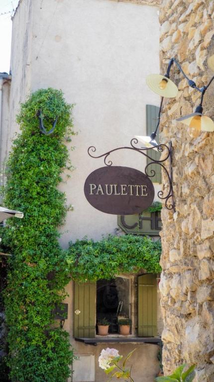 un panneau sur le côté d'un bâtiment avec des plantes dans l'établissement Maison Paulette, à Eygalières