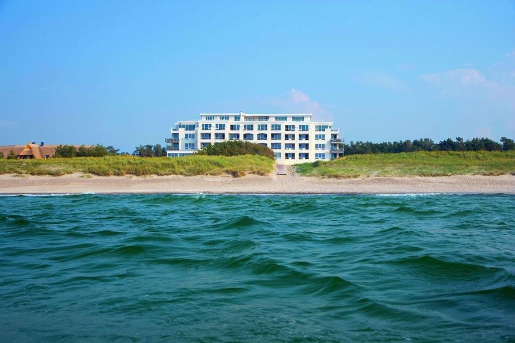 Strandhotel Dünenmeer - Adults only في ديارهاجين: مبنى كبير على الشاطئ بجوار المحيط