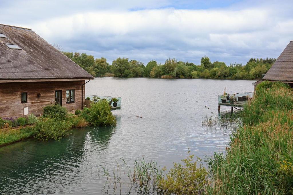 Blick auf einen See mit einem Haus und einem Dock in der Unterkunft Ardross Lodge in South Cerney
