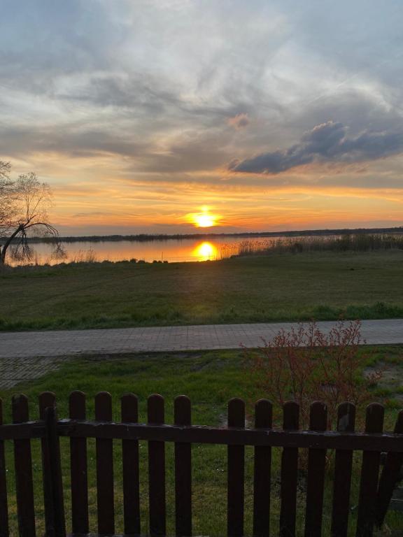 a sunset over a field behind a wooden fence at Ferienhaus am Schwielochsee in Friedland