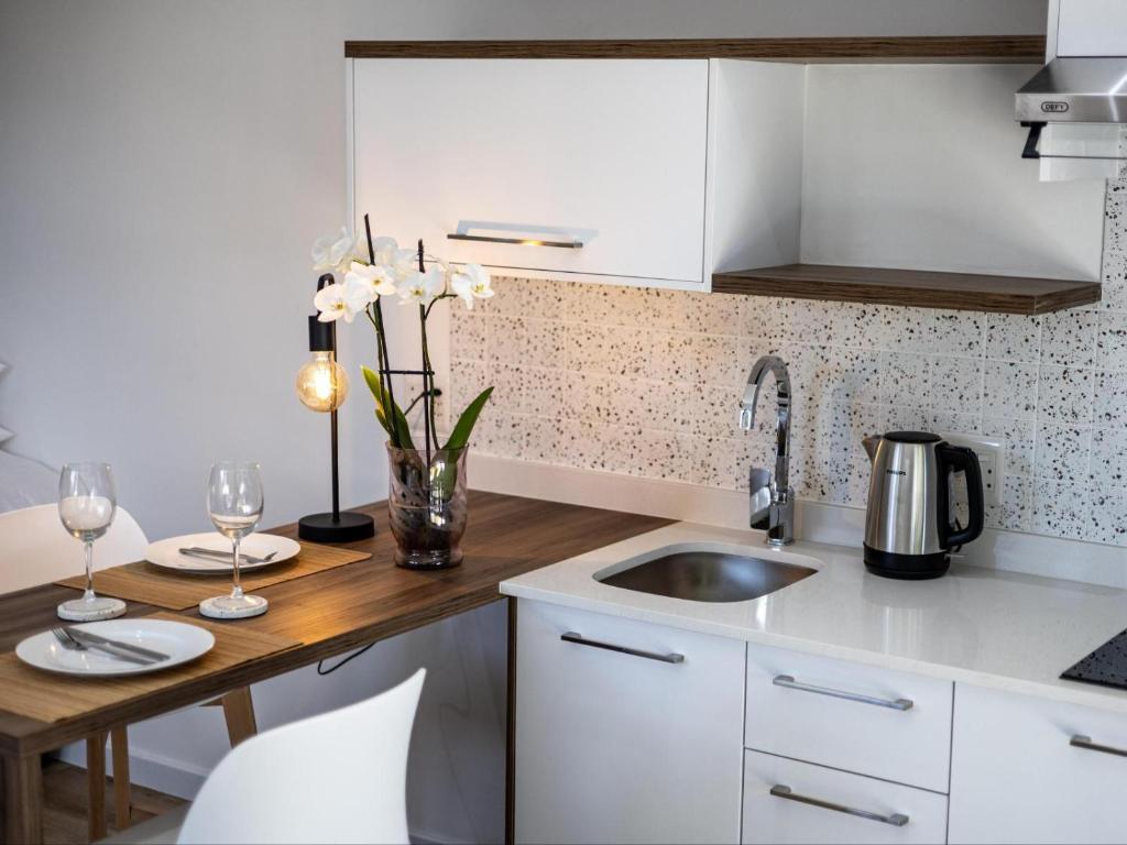 una cucina con mobili bianchi e un piano di lavoro in legno di Zonnekus Guesthouse a Città del Capo