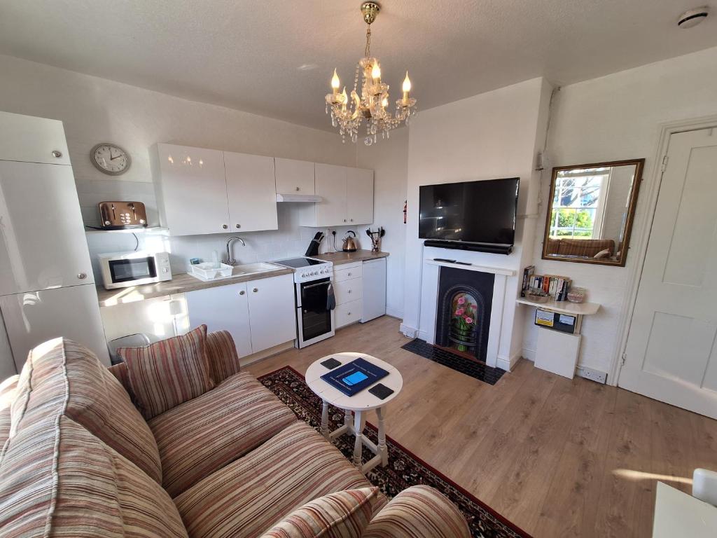 a living room with a couch and a kitchen at The Studio Apartment in Weymouth
