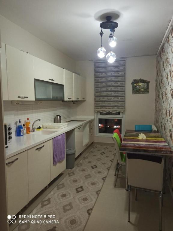 a kitchen with white cabinets and a table with chairs at ENTIRE 3 Bedroom Apartment with FREE PARKING in Esenyurt