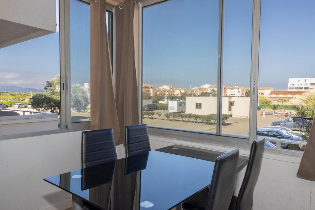 une salle à manger avec une table et des chaises et une grande fenêtre dans l'établissement Agréable Studio Port Leucate, à Leucate-Plage