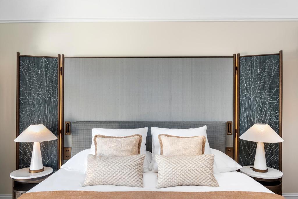 a bedroom with a large white bed with two lamps at Small Luxury Hotel Ambassador Zurich in Zürich