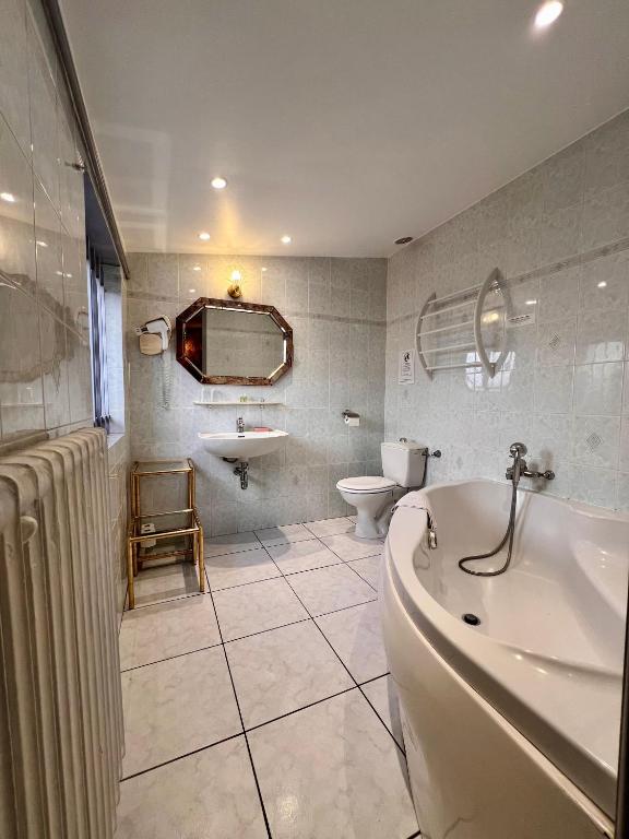 a bathroom with a tub and a toilet and a sink at Hotel Le Ponteil in Antibes