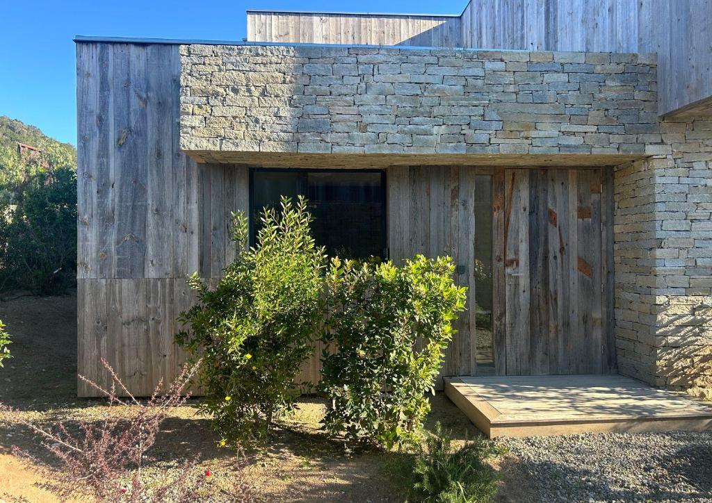 un bâtiment en bois avec un banc devant lui dans l'établissement Villa Les Lofts de Sainte Lucie, à Sainte-Lucie de Porto-Vecchio