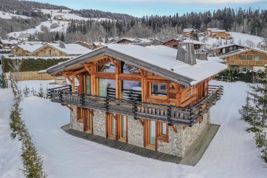 une image d'une maison en rondins dans la neige dans l'établissement Chalet Le Chardon Bleu, à Megève