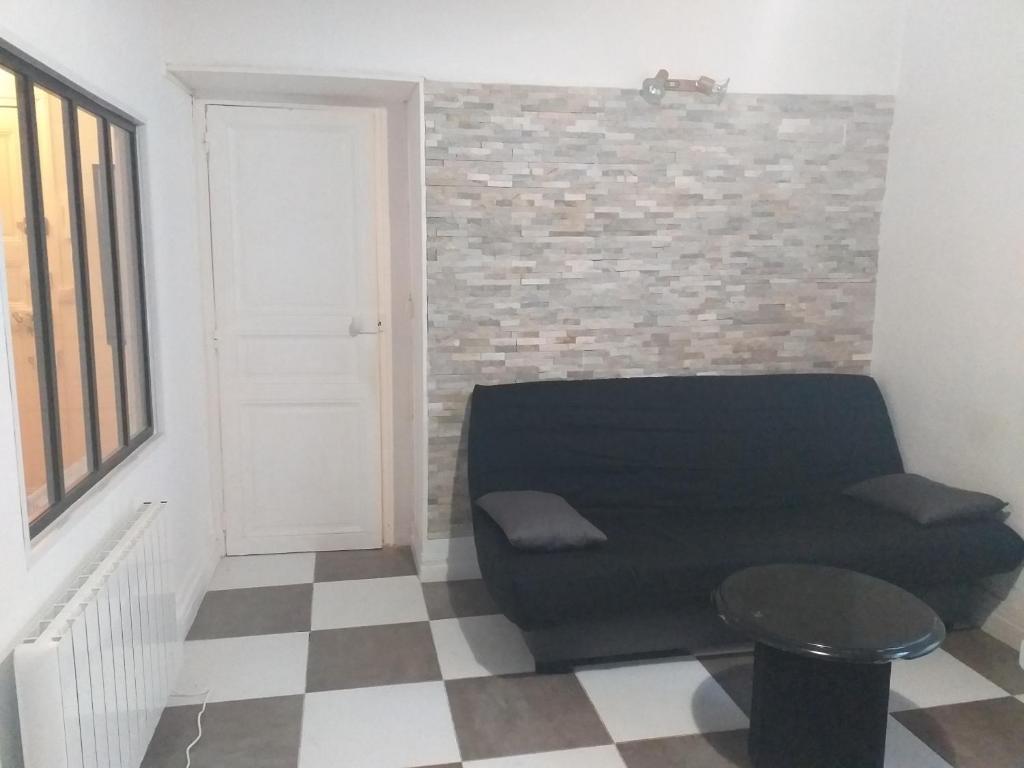 un salon avec un canapé et un mur de briques dans l'établissement T2 Centre ville Béziers, à Béziers