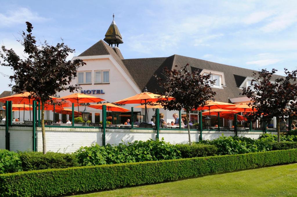 een restaurant met oranje parasols voor een gebouw bij Van der Valk Hotel Hilversum/ De Witte Bergen in Hilversum