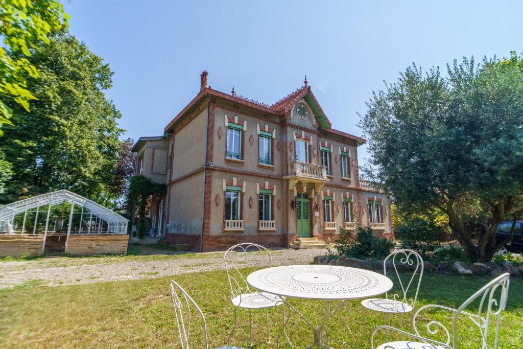 une grande maison avec une table en face dans l'établissement Maison de maitre et son parc, à Toulouse