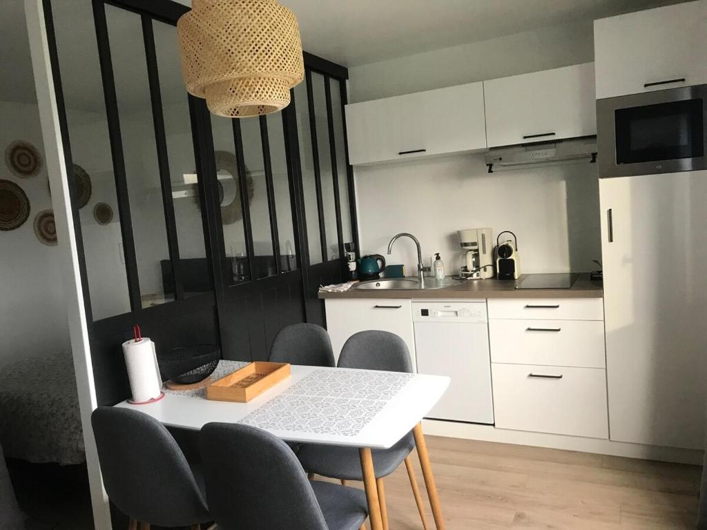 - une cuisine avec une table et des chaises blanches dans la chambre dans l'établissement Studio spacieux bord de mer, à Camiers