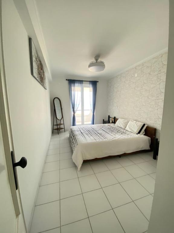 a white bedroom with a bed and a window at Apartamento Vista Mar in Praia da Vieira