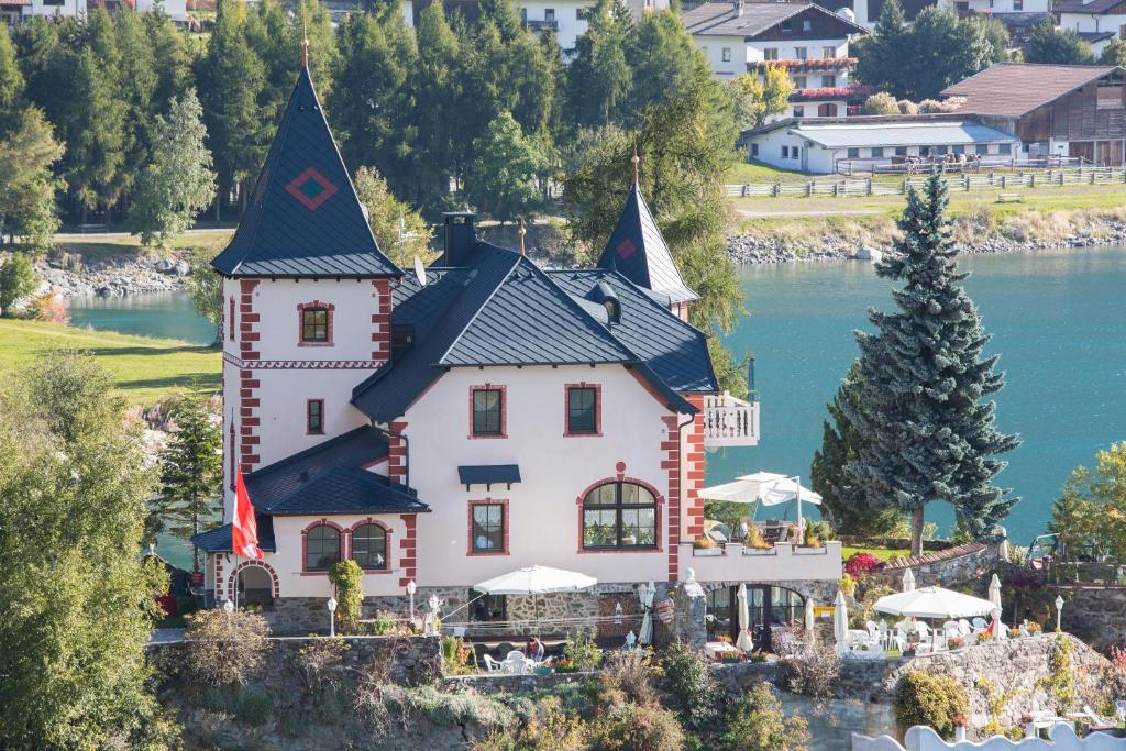 une maison sur une île dans l'eau dans l'établissement Hotel Schloesschen am See, à Resia