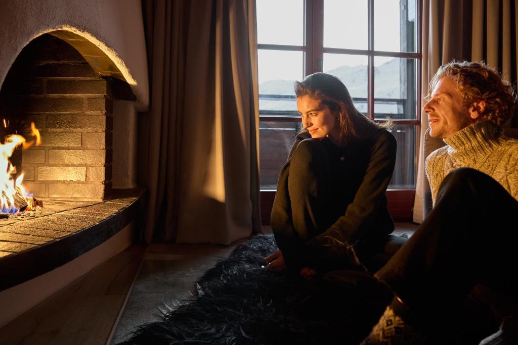 a man and a woman sitting in front of a fireplace at TOP Hotel Hochgurgl in Hochgurgl