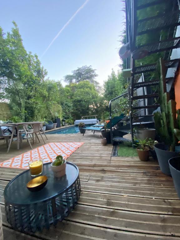 une terrasse en bois avec une table et une piscine dans l'établissement Maison pierre Bordeaux avec piscine chauffée, à Bordeaux