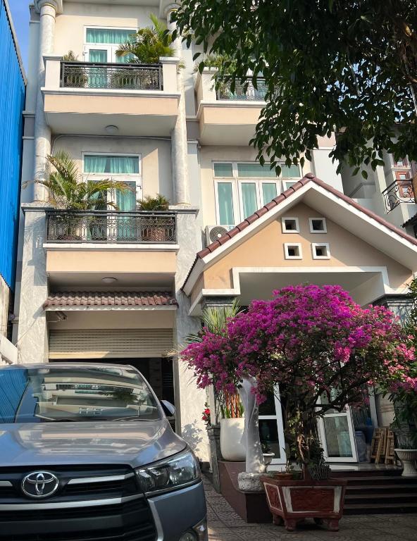 a car parked in front of a building with flowers at The Sun Hotel in Long Bình