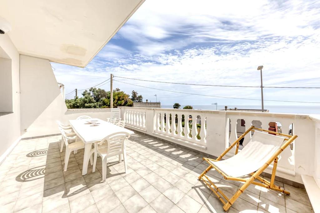 a patio with white chairs and tables on a balcony at Le Carrube Vista Mare in Andrano