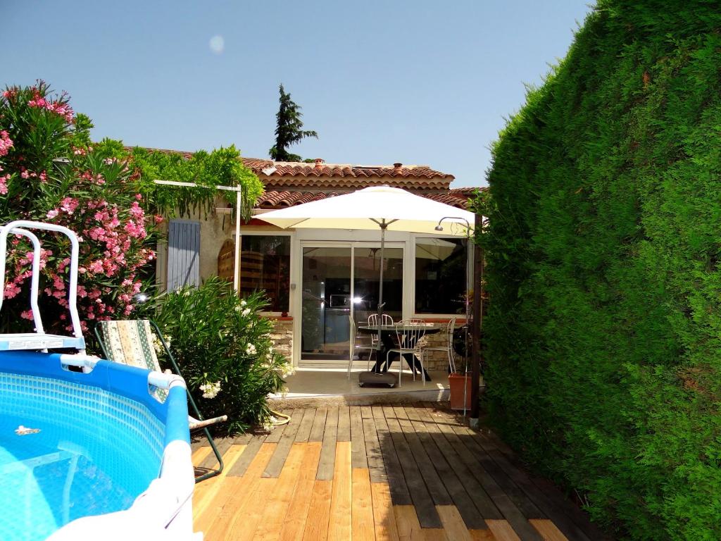 ヴデーヌにあるDuplex En Provenceの裏庭(プール付)と家(傘付)