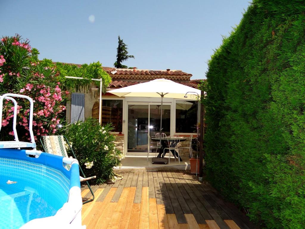 a backyard with a pool and a house with an umbrella at Duplex En Provence in Vedène