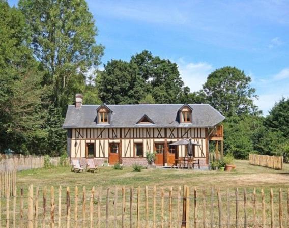 une grande maison dans un champ à côté d'une clôture dans l'établissement Gîte du rouge gorge Normandy, à Illeville-sur-Montfort
