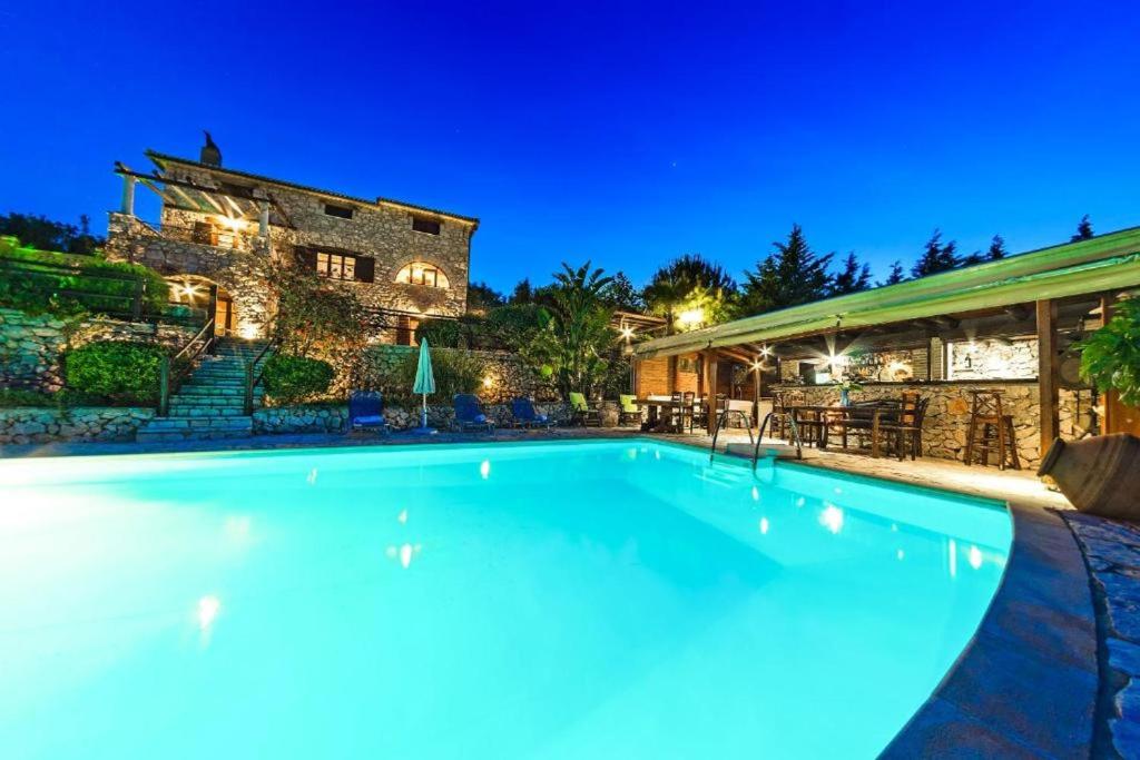 a swimming pool in front of a house at night at Villa Poseidon Residences - Poolside Zante Nests in Skinária