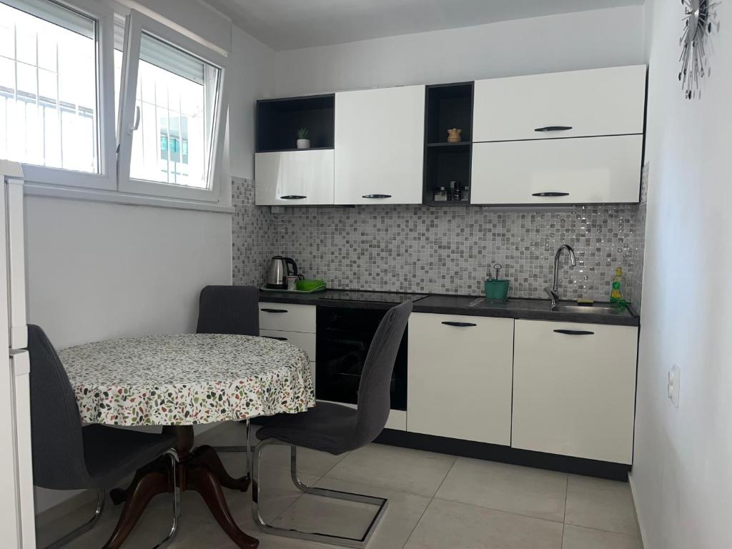 cocina con armarios blancos, mesa y fregadero en Apartman Bubi, en Zadar