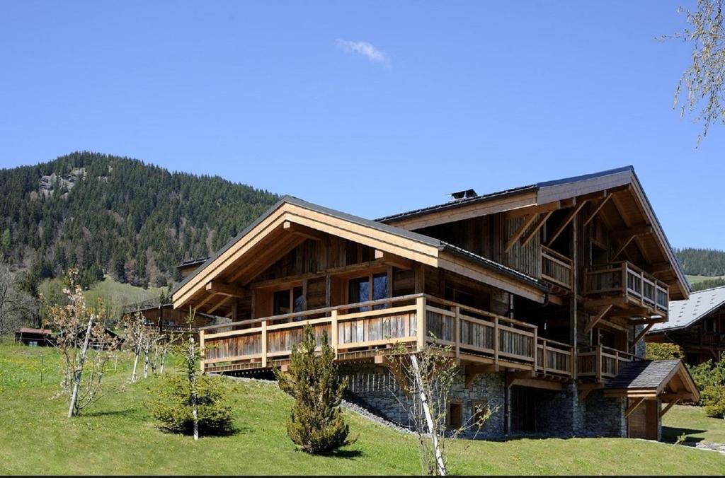 a large wooden house in a field with a mountain at Chalet Le Prariand - Megève in Megève