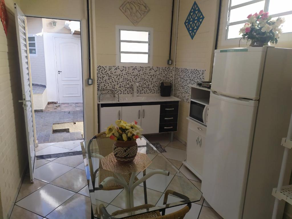 a kitchen with a glass table and a refrigerator at Pousada - Flat - Kitnet - Mobiliada, Confortável e Perto de Tudo in Atibaia