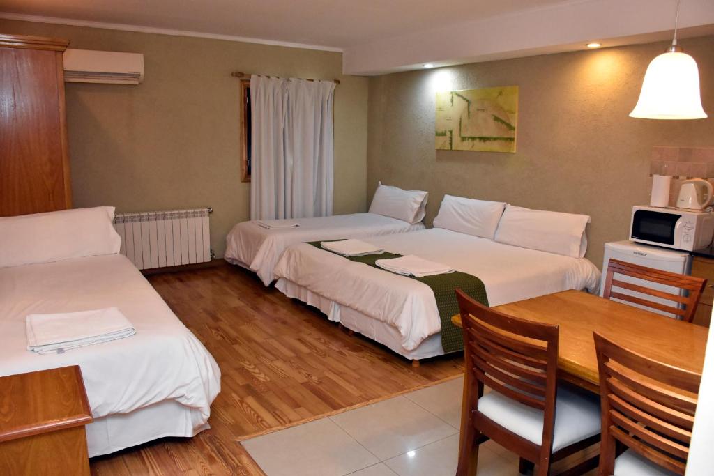 a hotel room with two beds and a table at Bahia Belgrano Suites in Bahía Blanca