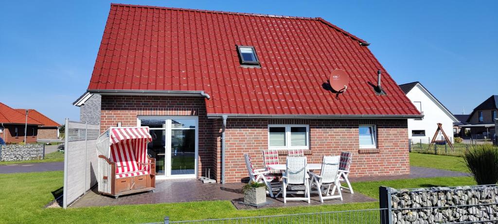 une maison au toit rouge avec une table et des chaises dans l'établissement Ferienhaus Wangermeer, à Wangerland