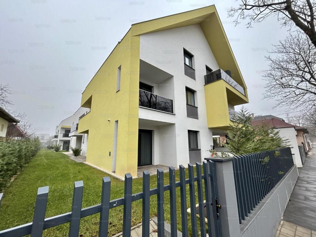 a yellow and white house behind a fence at Gold Residence Apartman in Hajdúszoboszló