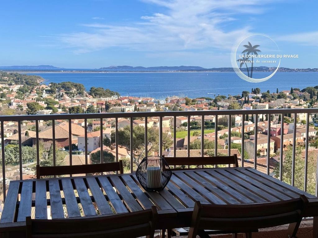 - un banc en bois sur un balcon avec vue sur l'eau dans l'établissement Entre Ciel et Mer - Vue panoramique - Plages à 1km, à Carqueiranne