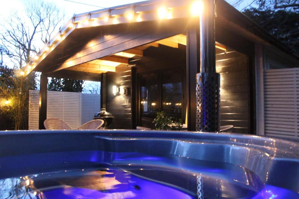 a hot tub in front of a house with lights at Caban Y Tan Dderwen with private Wood Fired Hot Tub in Chwilog
