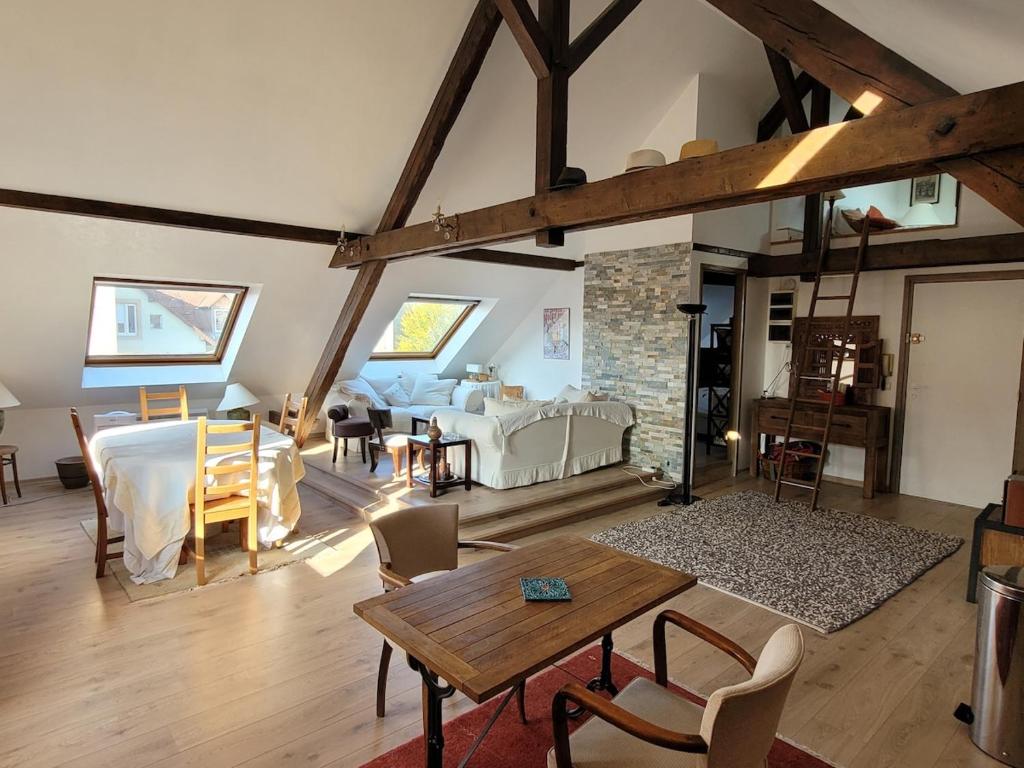 Una gran sala de estar con mesa y sillas. en Escapade Romantique, en Schiltigheim