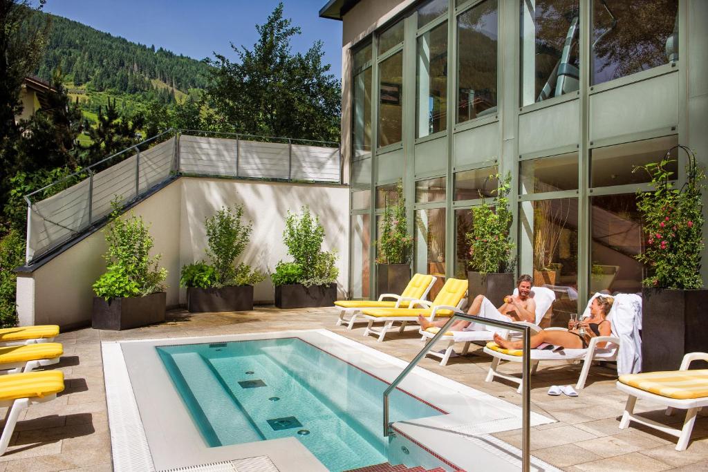 two people sitting in chairs next to a swimming pool at Familienhotel Sonngastein in Bad Gastein