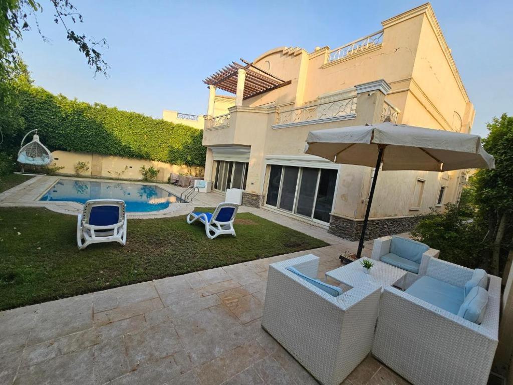a house with a pool and two chairs and an umbrella at فيلا فاخرة للايجار حمام سباحة التجمع الخامس in Cairo