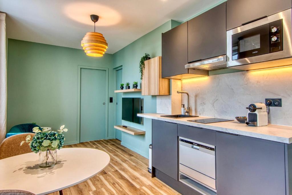 une cuisine avec des armoires bleues et une table dans l'établissement Le Cèdre Bleu - Bel appart climatisé quartier point du jour Lyon 5, à Lyon