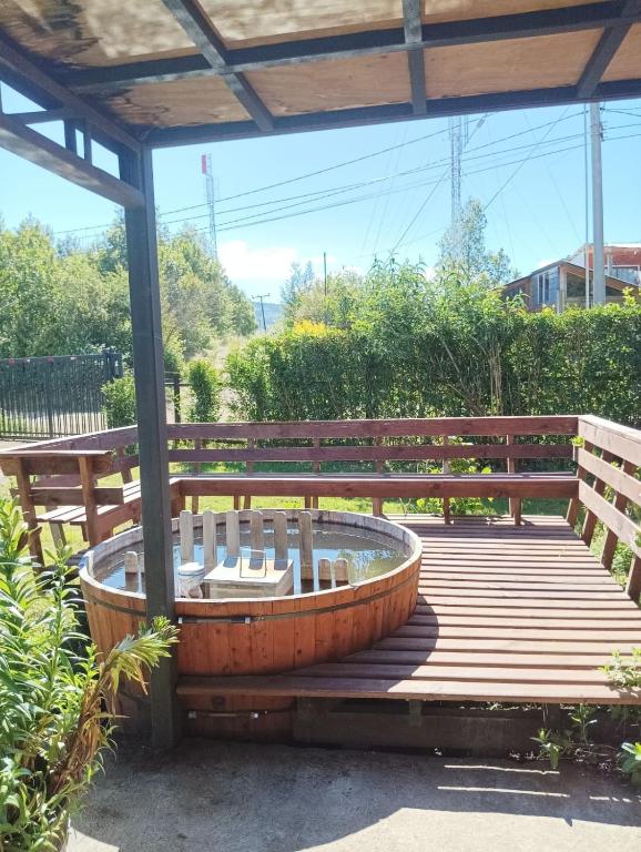 a wooden deck with a hot tub and a bench at Casa Tinaja Quincho in Licán Ray