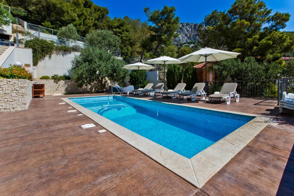 a swimming pool with chairs and umbrellas in a yard at Luxurious Apartments Maslina with Beach in Milna