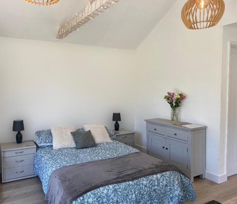 a bedroom with a bed and two dressers with flowers on it at The Garden Room in Henley on Thames