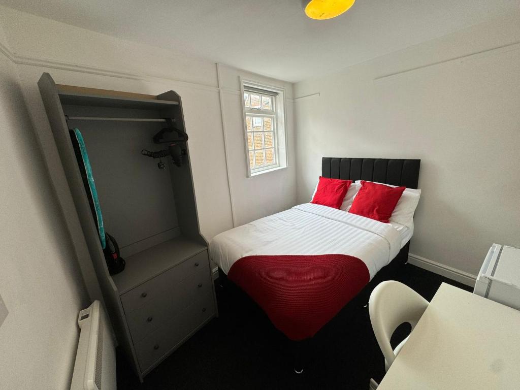 a small room with a bed with red pillows at St James's Terrace Studio Rooms in Nottingham
