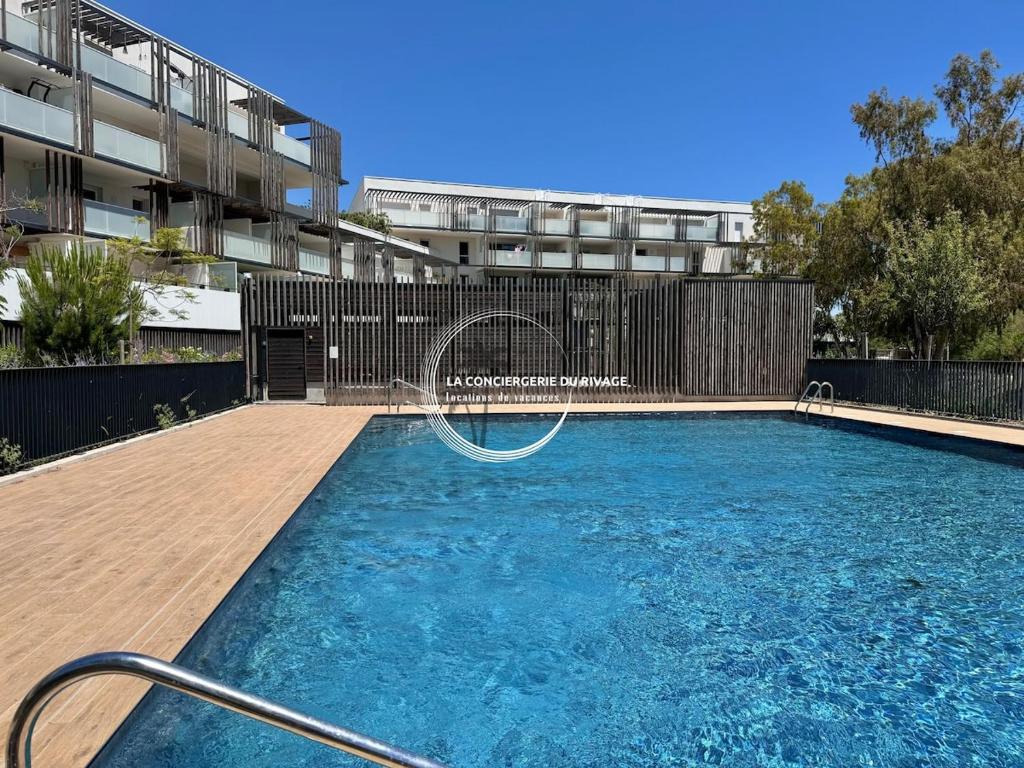 une piscine avec toboggan en face d'un bâtiment dans l'établissement L'Horizon - Piscine - À 50m de la plage, à Hyères