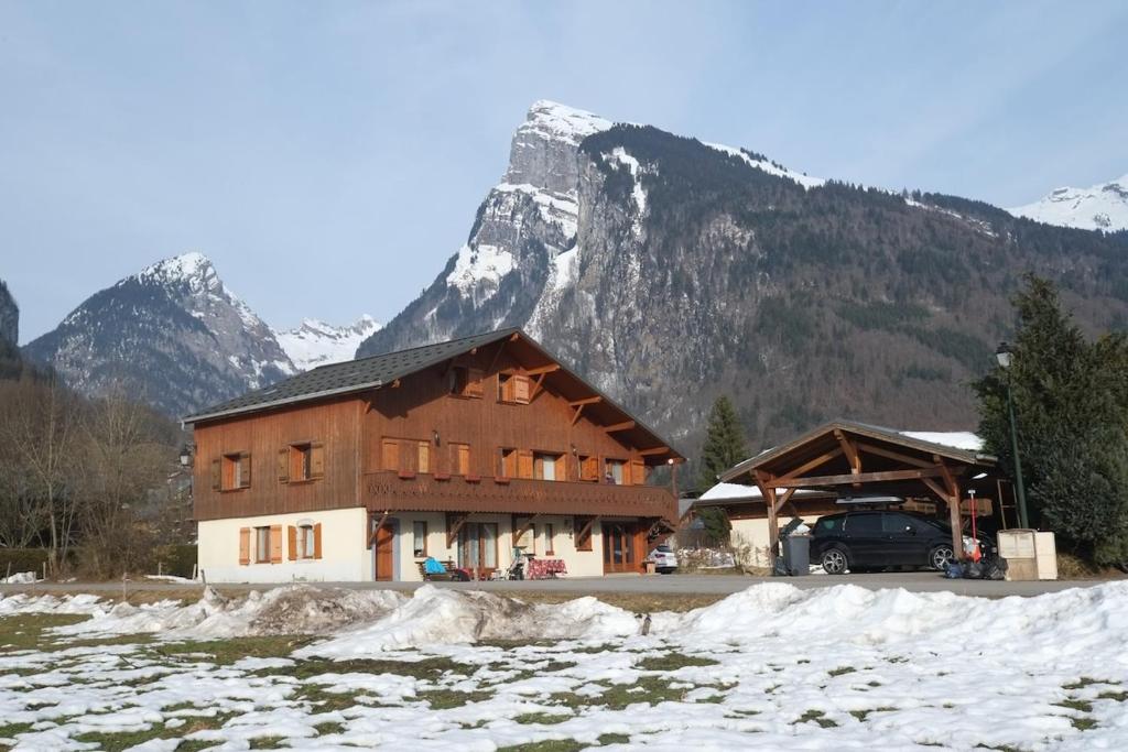 un grand bâtiment en bois avec une montagne en arrière-plan dans l'établissement Appartement 7 personnes, Samoëns, à Samoëns