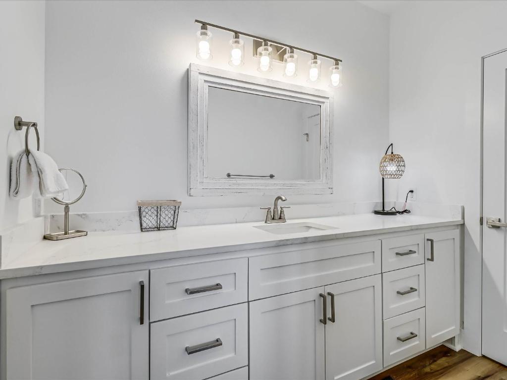 Un baño blanco con lavabo y espejo. en Nautical Nest, en Rockport
