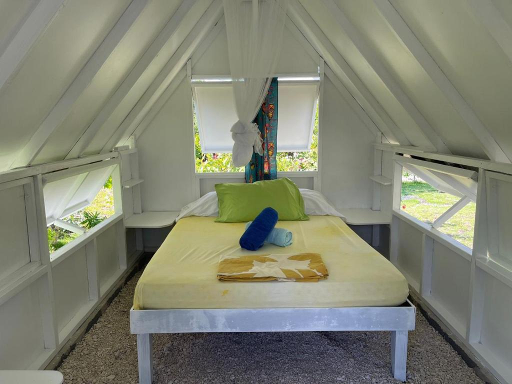 un letto in una piccola stanza con due finestre di Alaroots Fakarava a Fakarava