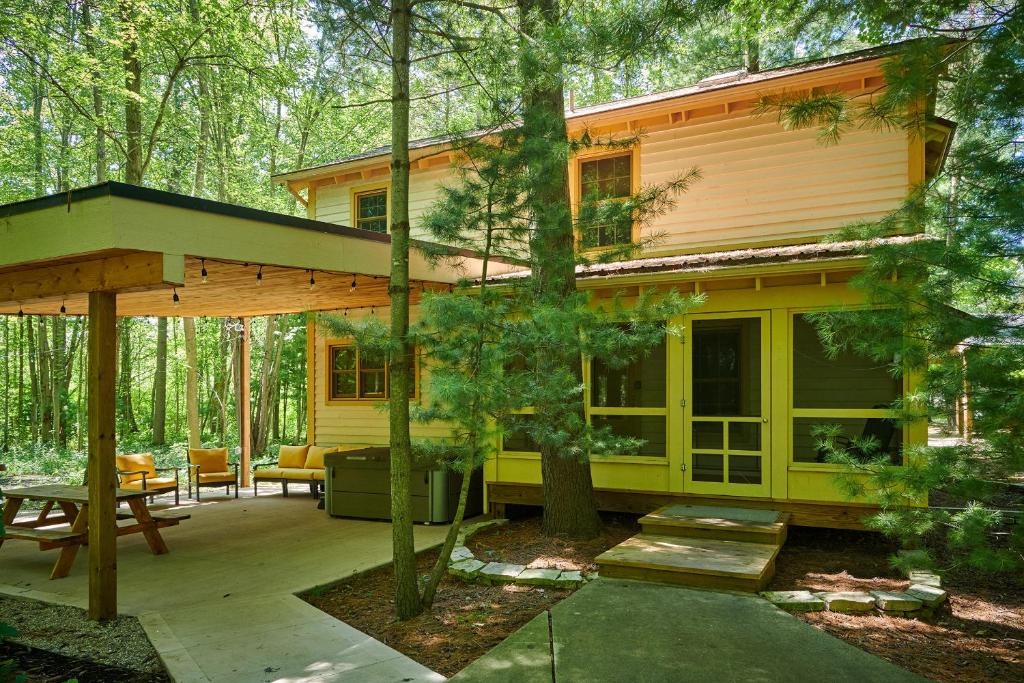 a small yellow house with a patio in the woods at Dollybrook Cottage 1 Pet Friendly Community Pool Groups Welcome in Fennville